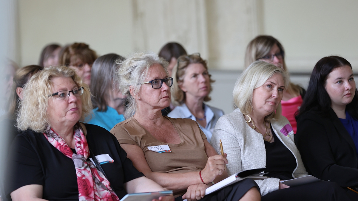 mehrere Frauen sitzen in einem Raum und hören zu