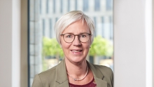 Frau mit kurzen Haaren, Brille vor einem Fenster