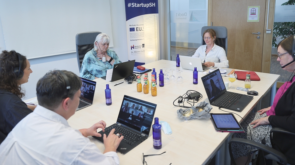 fünf Frauen sitzen um einen Tisch und halten eine digitale Pressekonferenz ab