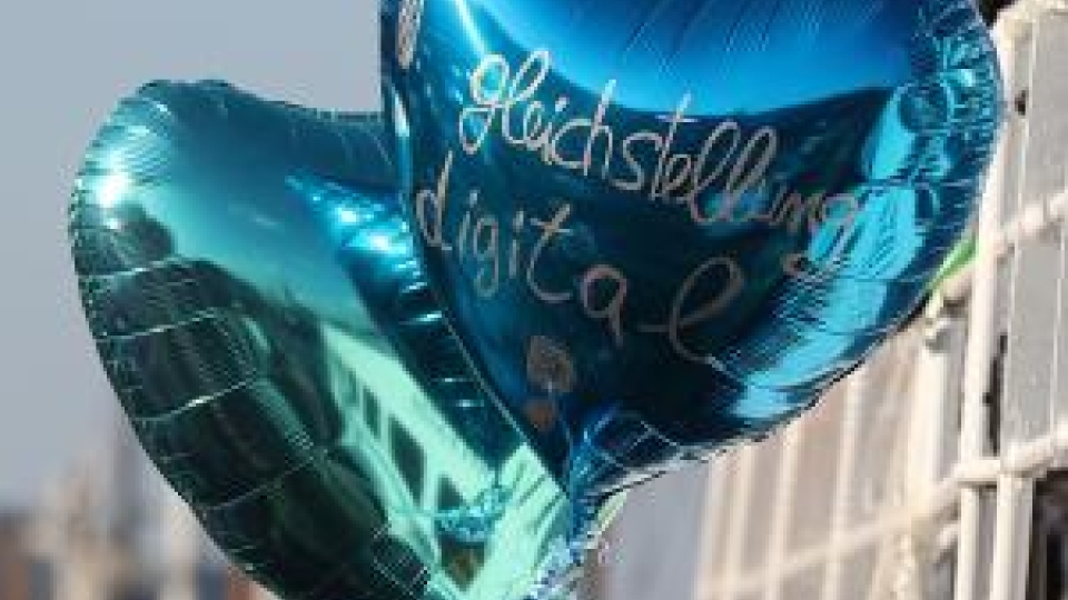 zwei herzförmige Luftballons mit der Aufschrift Gleichstellung digital fliegen in der Luft
