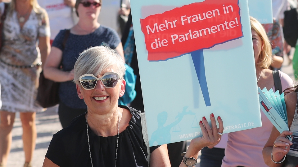Frau mit Plakat: mehr Frauen in die Parlamente