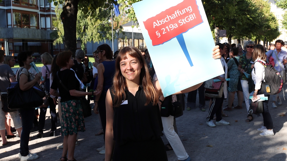 junge Frau mit Plakat mit Schrift: Weg mit § 218
