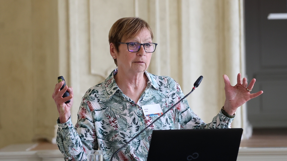 Frau mit kurzen Haaren und Brille steht hinter Rednerpult