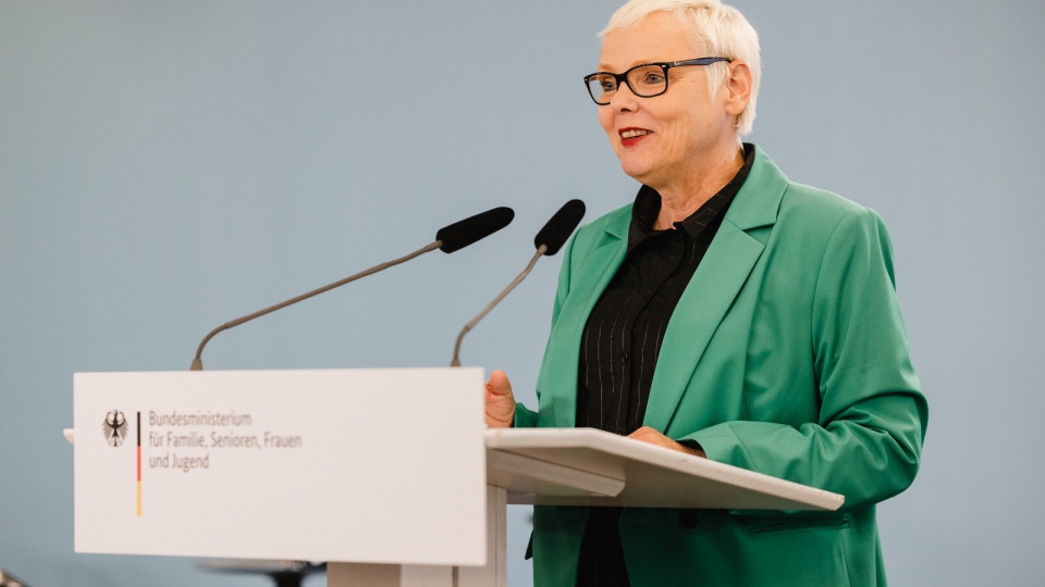 Frau mit kurzen weißen Haaren,  Brille und grünem Jacket