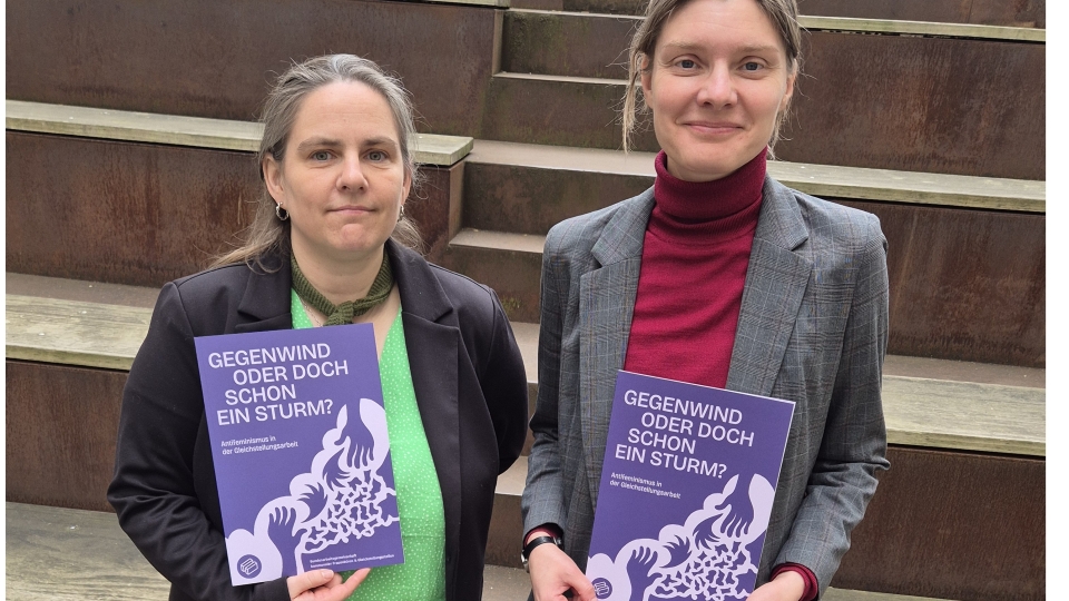 zwei Frauen haben die lilafarbenen Handreichungen in der Hand