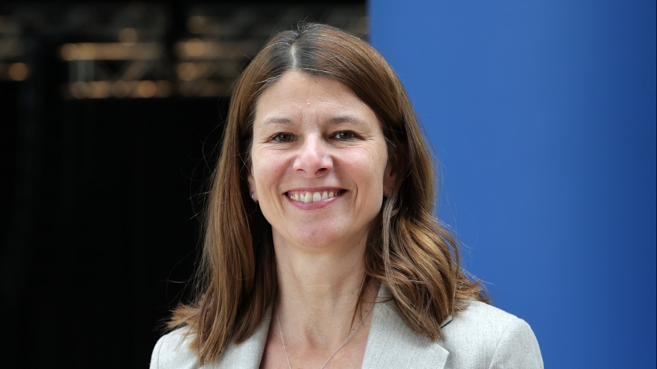 Frau mit hellem Sakko und mittellangen Haaren
