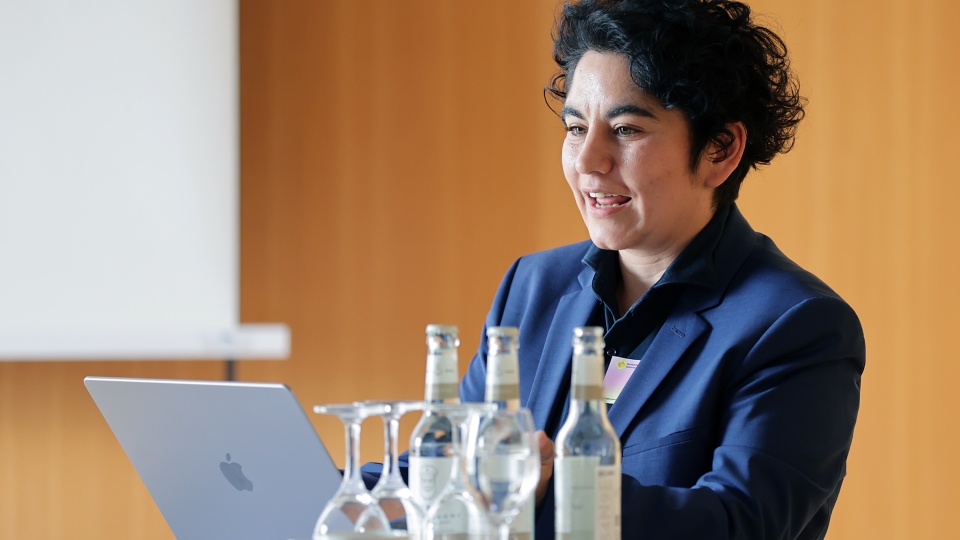 Person mit kurzen gelockten Haaren vor Laptop