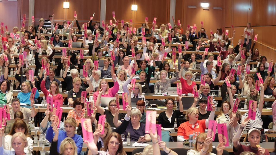 ein Saal voller Frauen mit pinken Stimmzettel