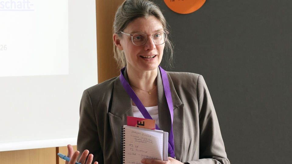 blonde Frau mit Pferdeschwanz und Brille spricht