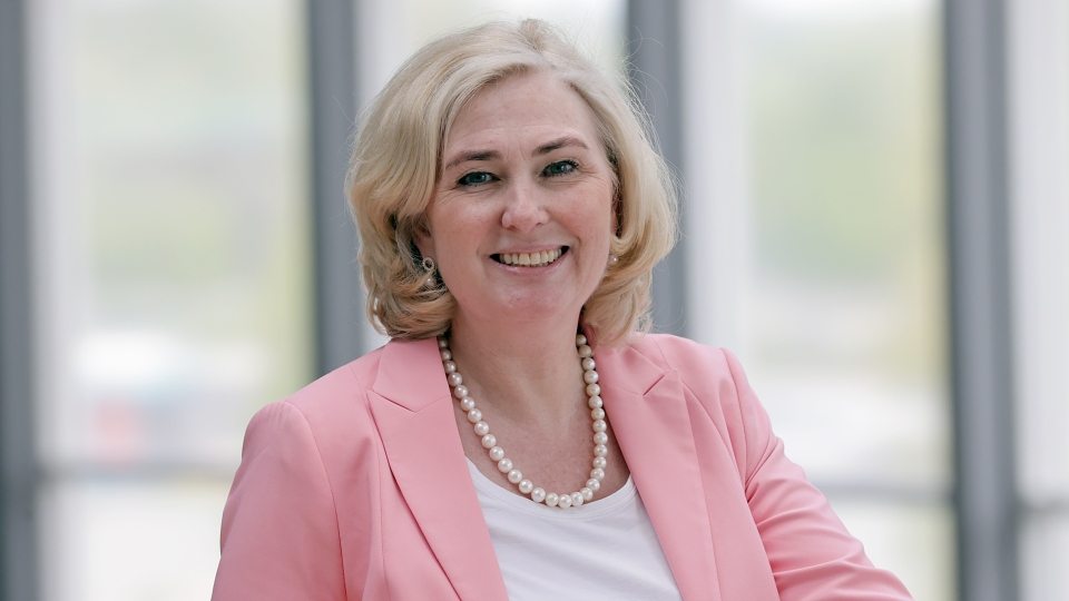 Frau mit rosa Jacke und blonden Haaren
