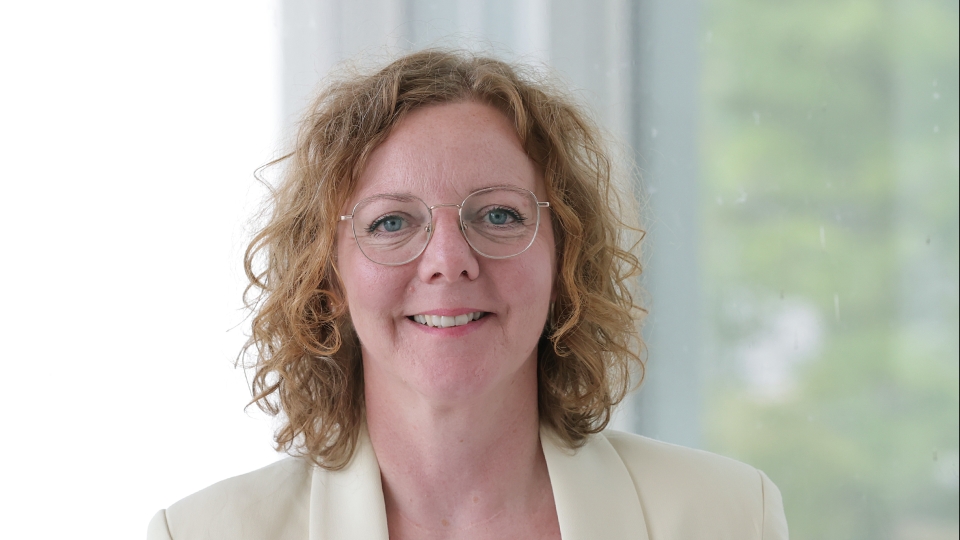 Frau mit roten Locken und hellem Sakko